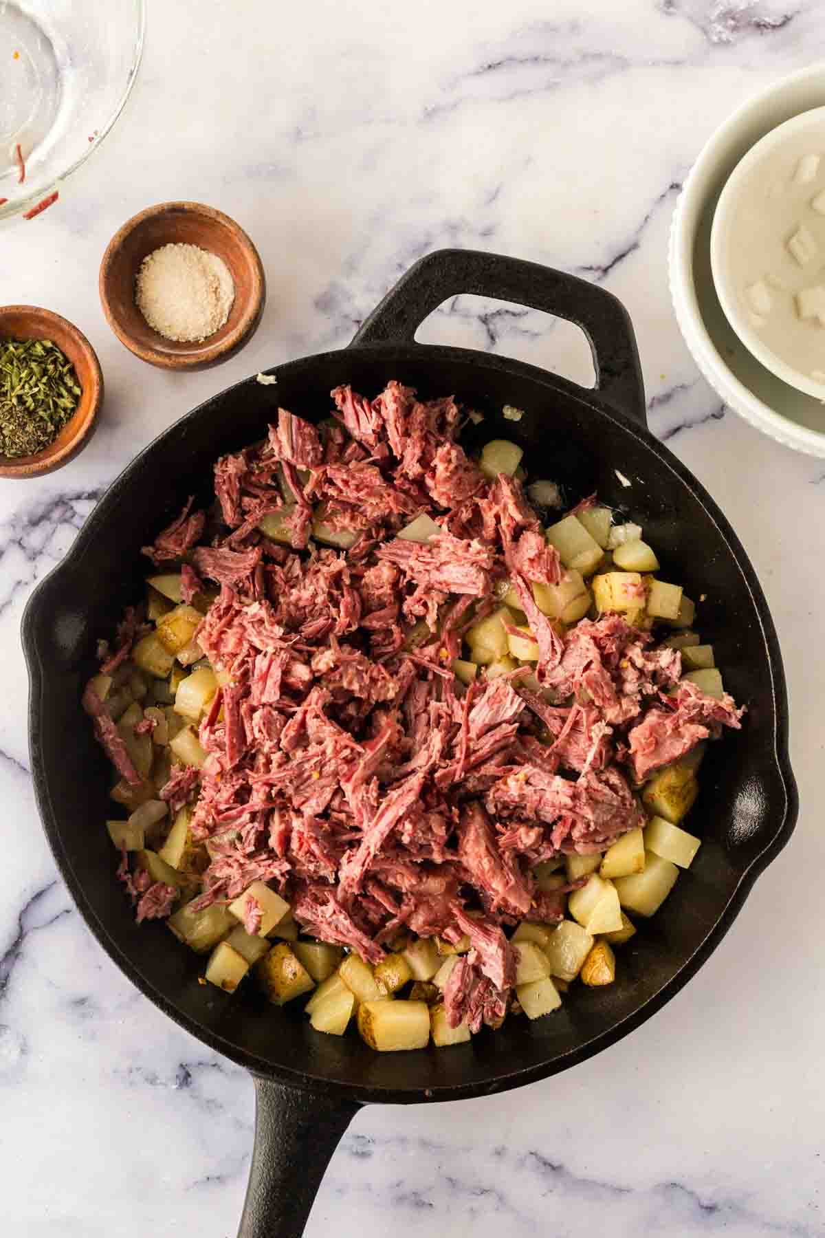 Shredded beef added to the skillet of corned beef hash.