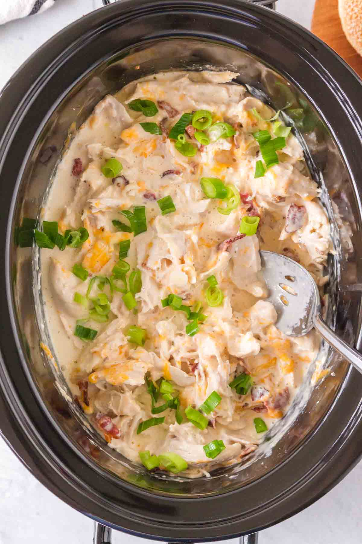 slow cooker with seasoned crack chicken inside shredded and sauced