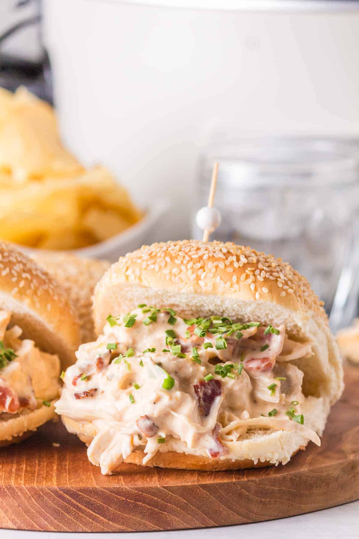 shredded and saucy crack chicken between sesame buns on a wooden board