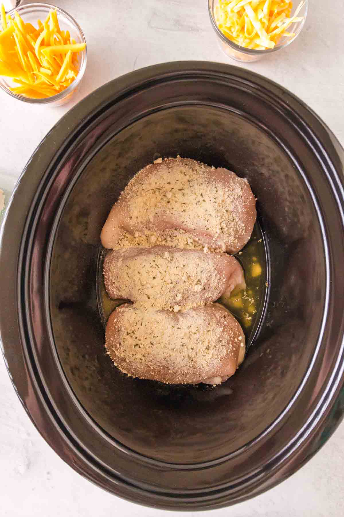 slow cooker with seasoned crack chicken inside