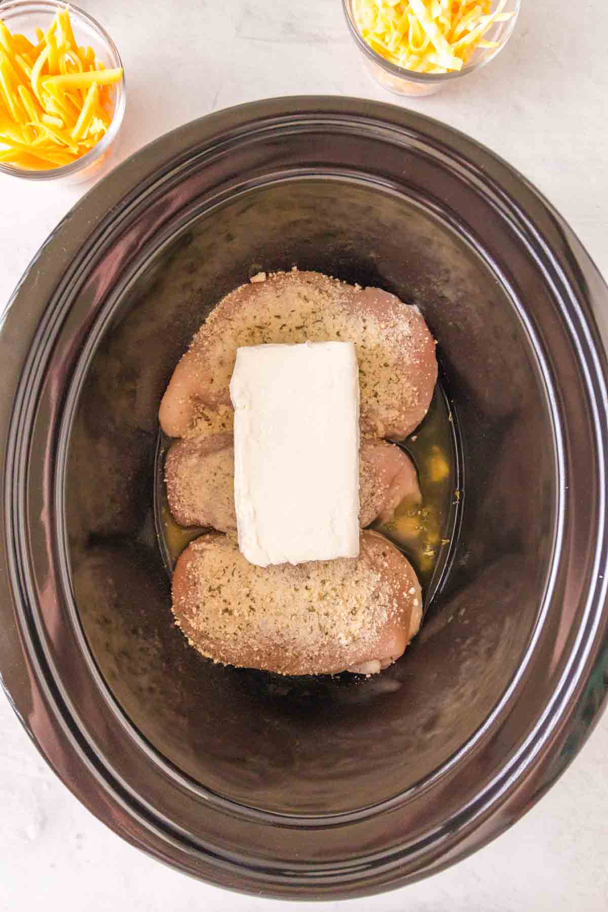 slow cooker with seasoned crack chicken inside