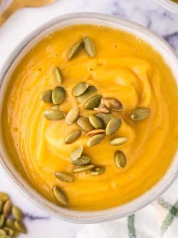 top view of a white bowl of roasted butternut squash soup with pumpkin seeds on top