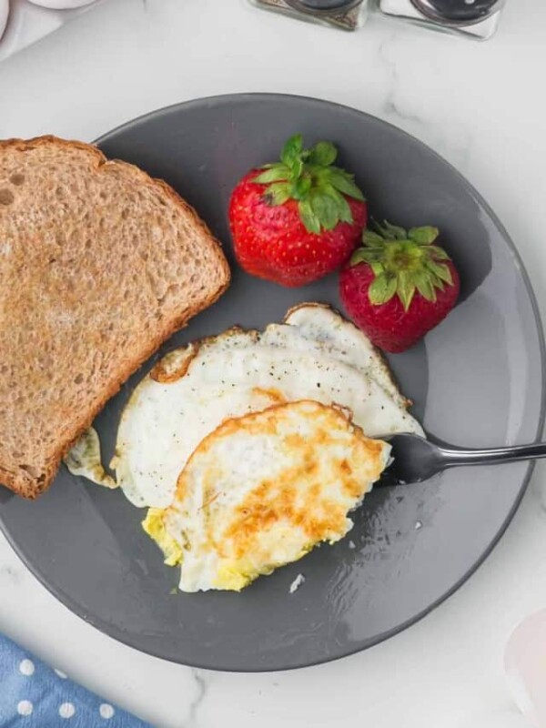 grey plate with toast and a fried egg on the side with strawberries