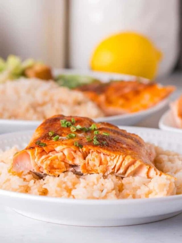 white plate with baked salmon recipe over rice.