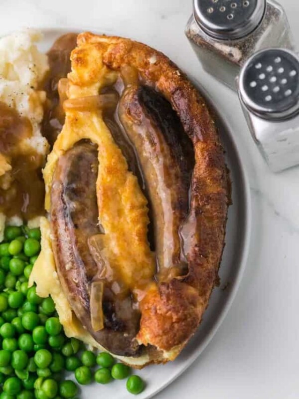top view of plated serving of toad in a hole recipe with mash potato and peas.
