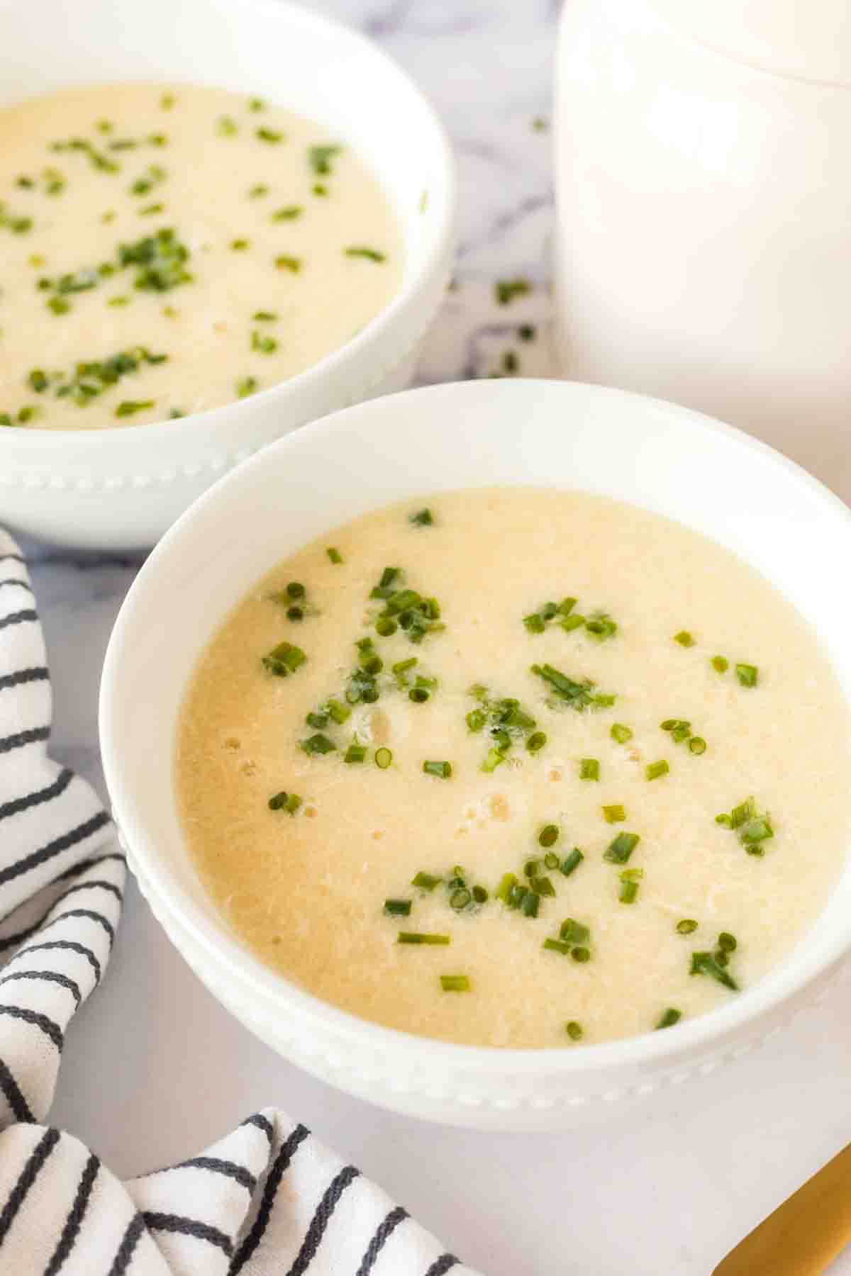 egg drop soup in white bowls with herbs on top