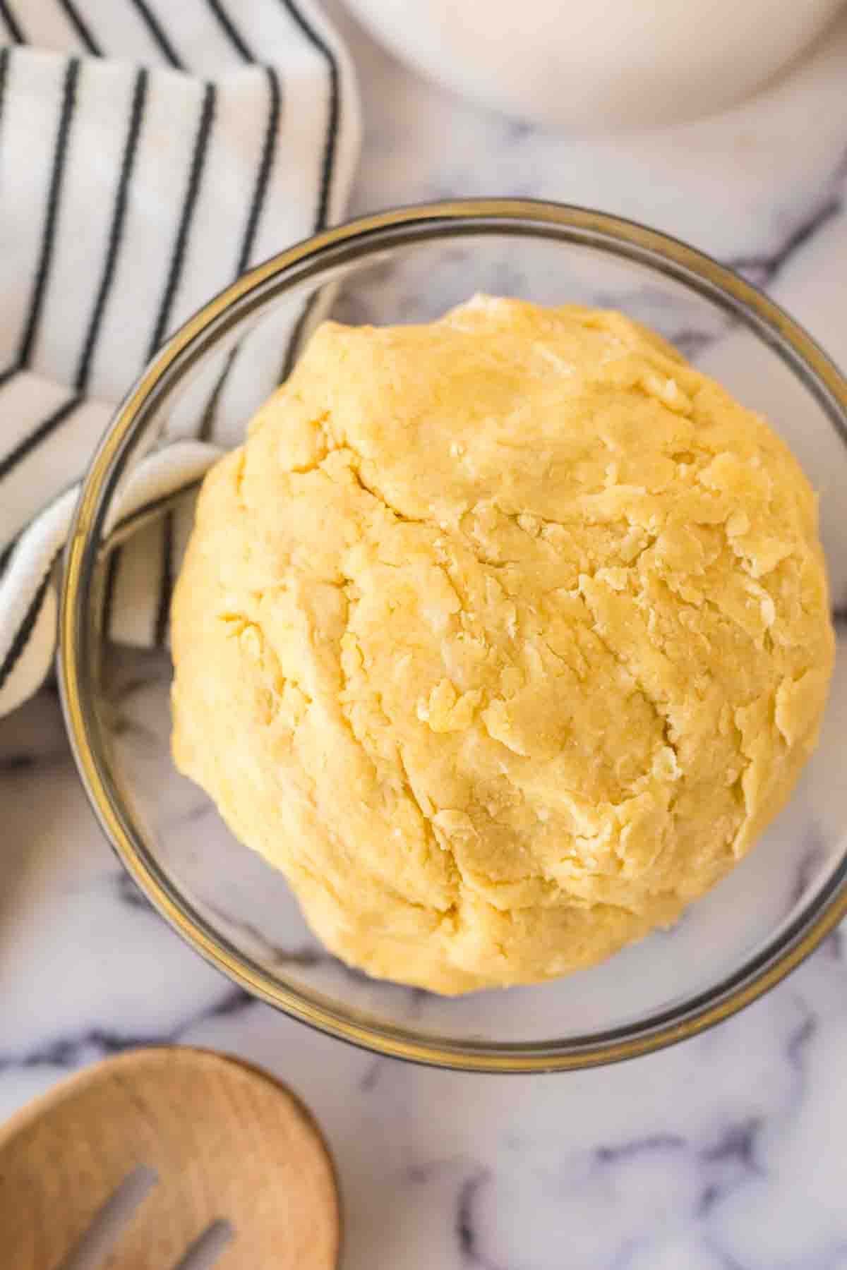 top view of a clear mixing bowl with empanada dough ball inside