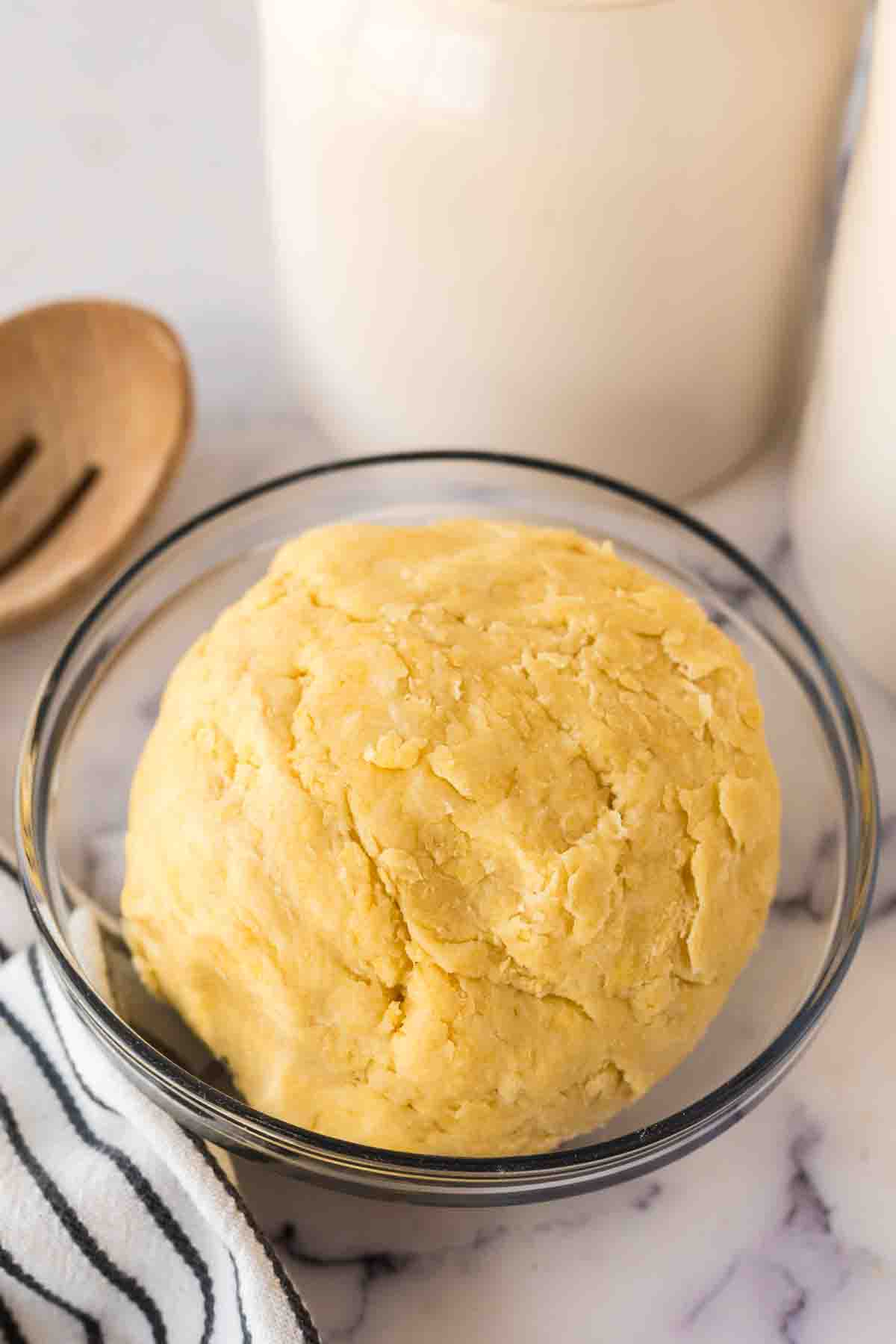 clear mixing bowl with empanada dough ball inside