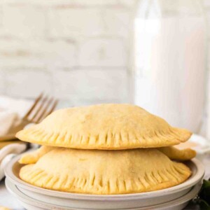 side view of a round plate with two empanadas stacked on it