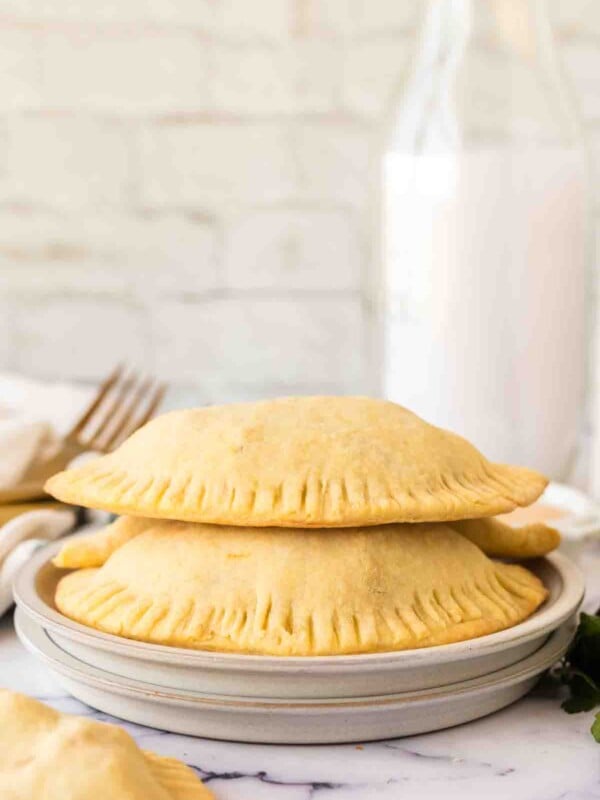 side view of a round plate with two empanadas stacked on it