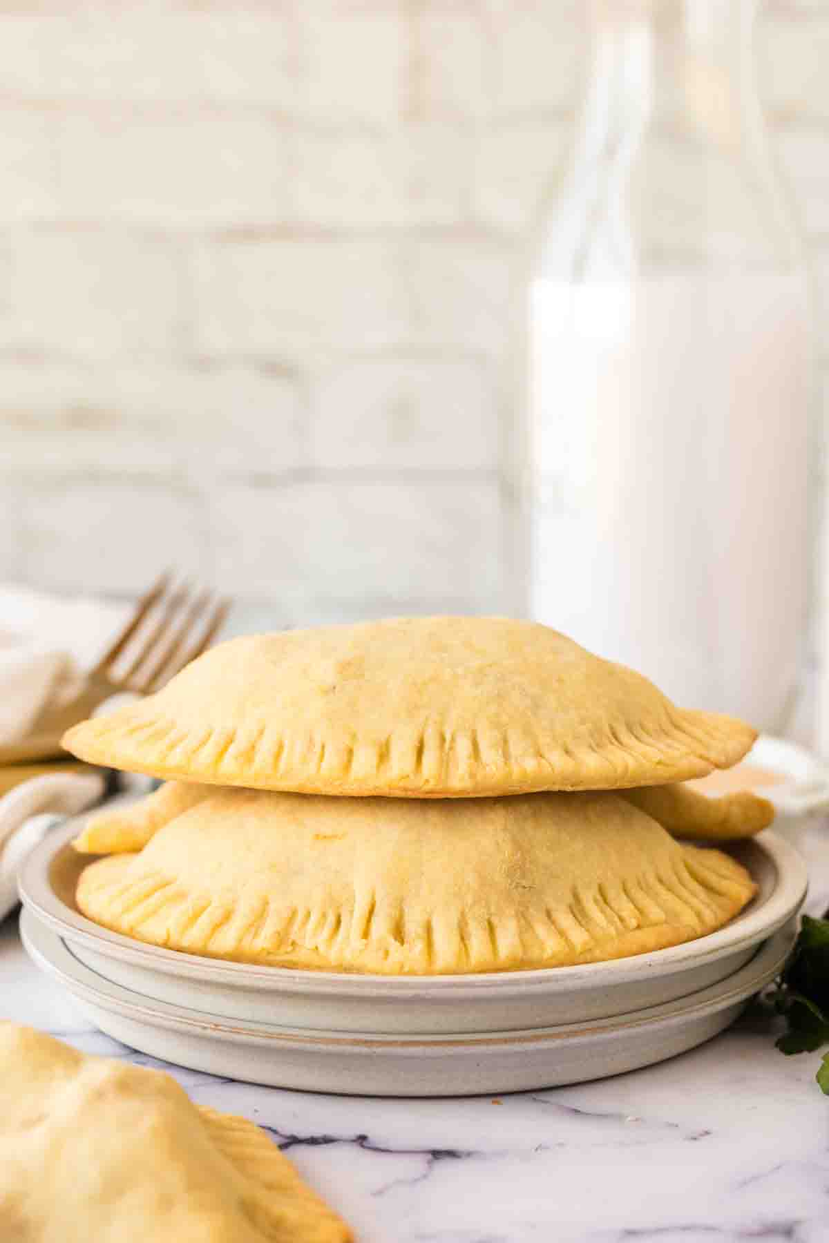 side view of a round plate with two empanadas stacked on it