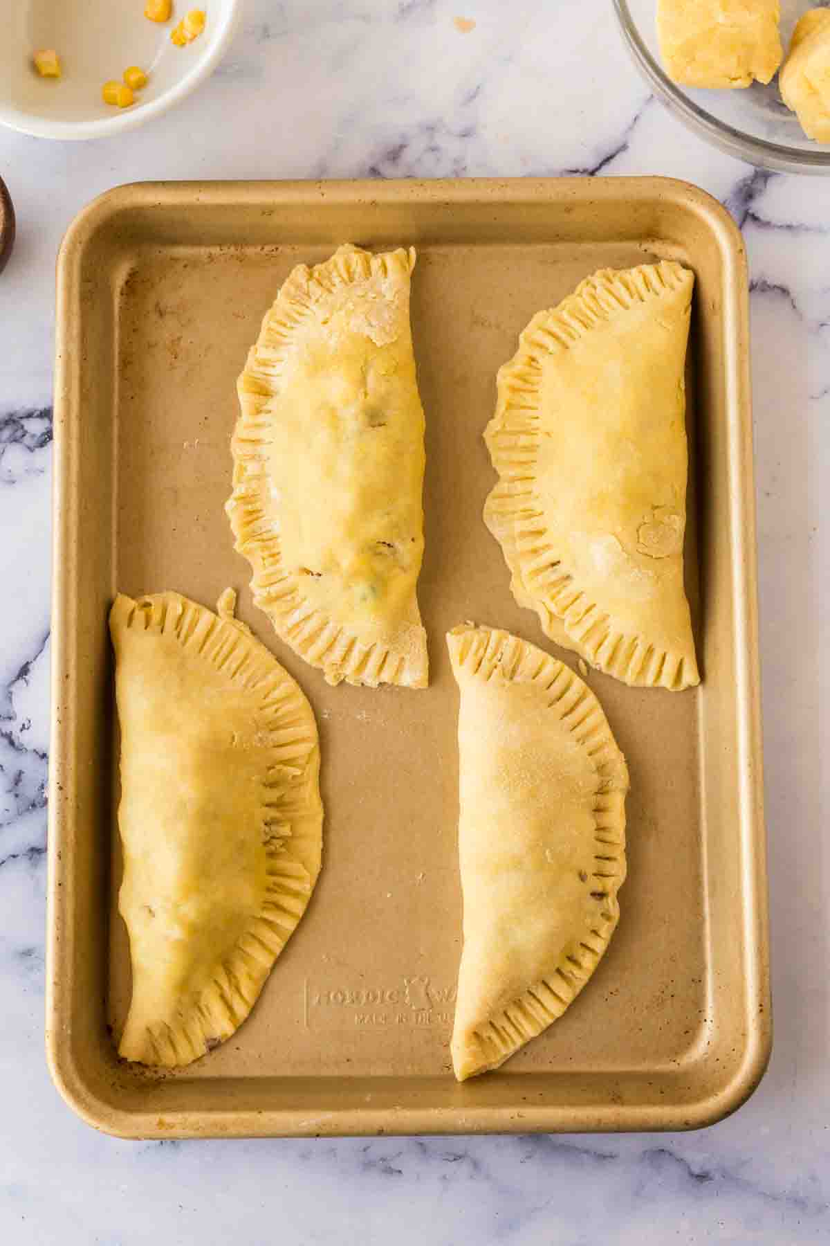 raw empanadas on a baking dish