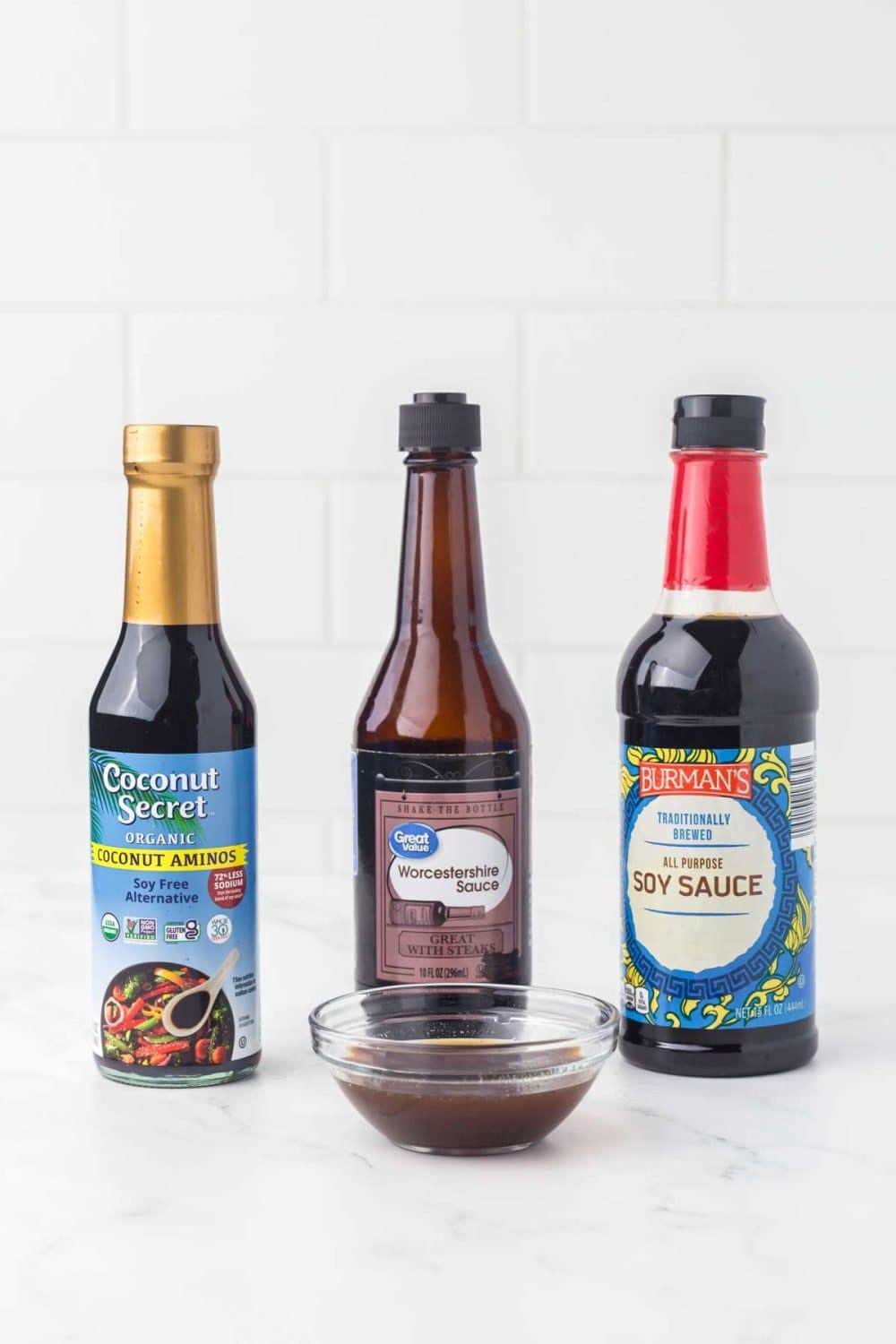 three bottles of ingredients for fish sauce substitutes with a small clear dish in front