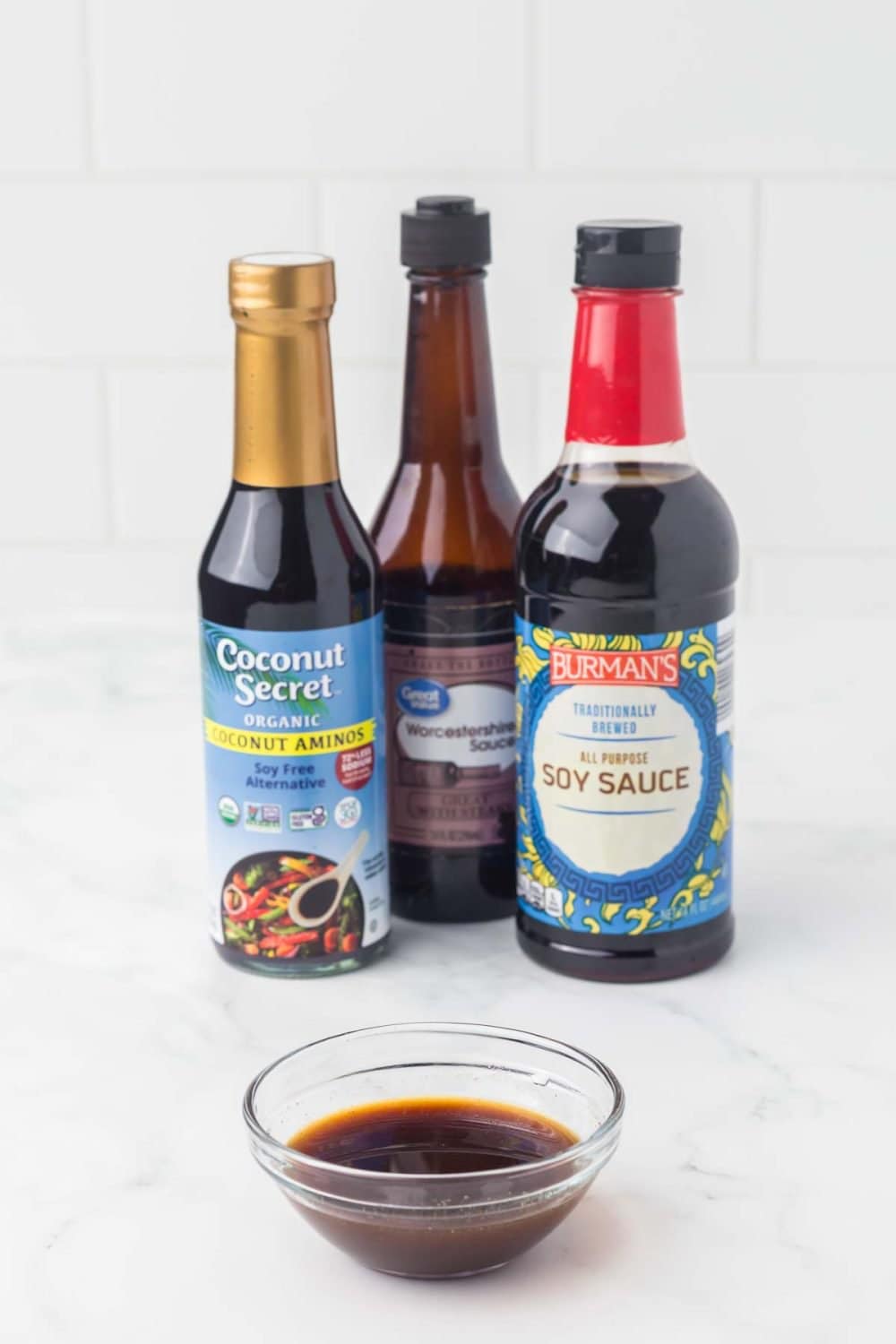 three bottles of ingredients for fish sauce substitutes with a small clear dish in front