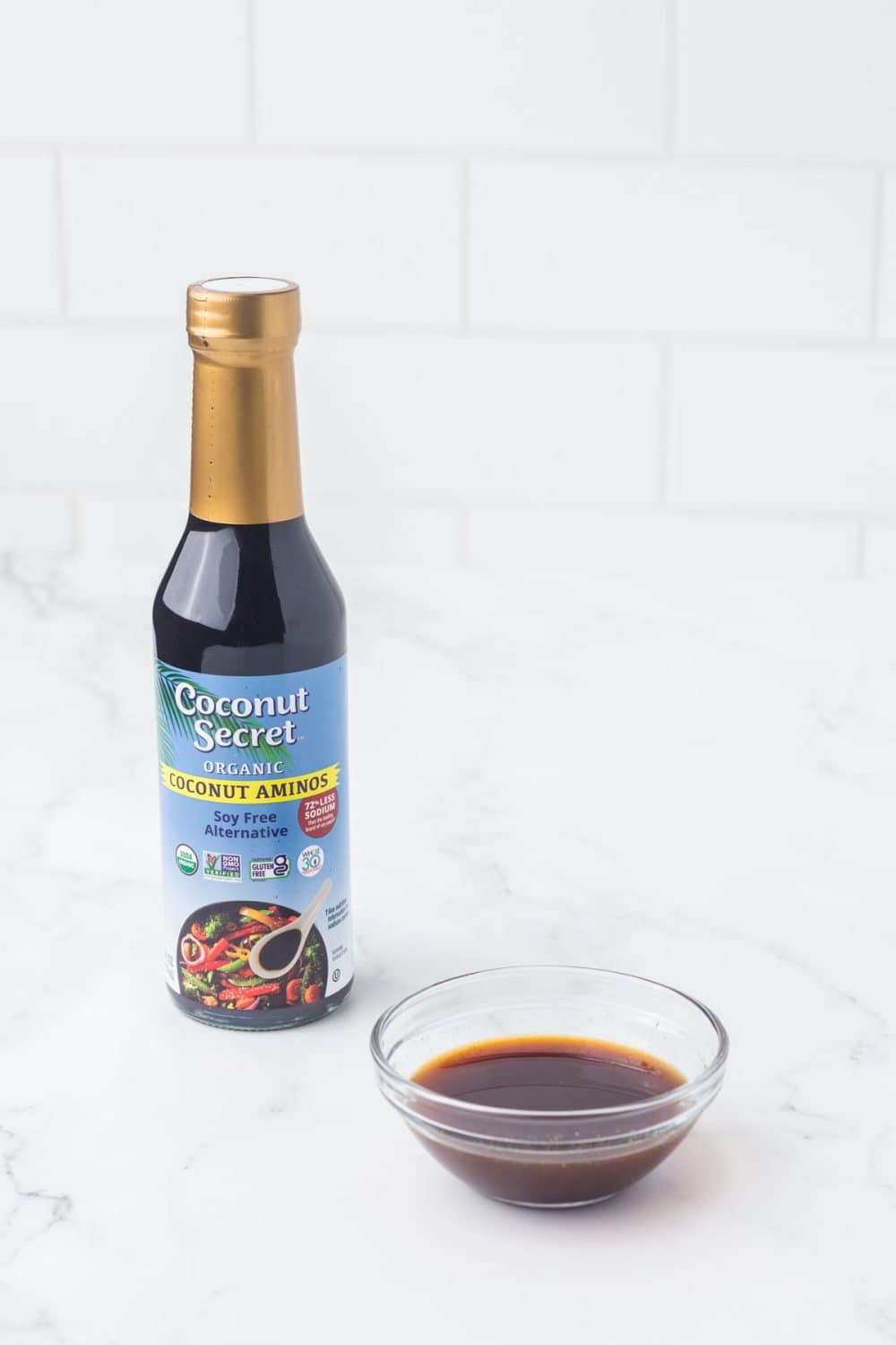 one bottle of coconut secret for fish sauce substitutes with a small clear dish in front