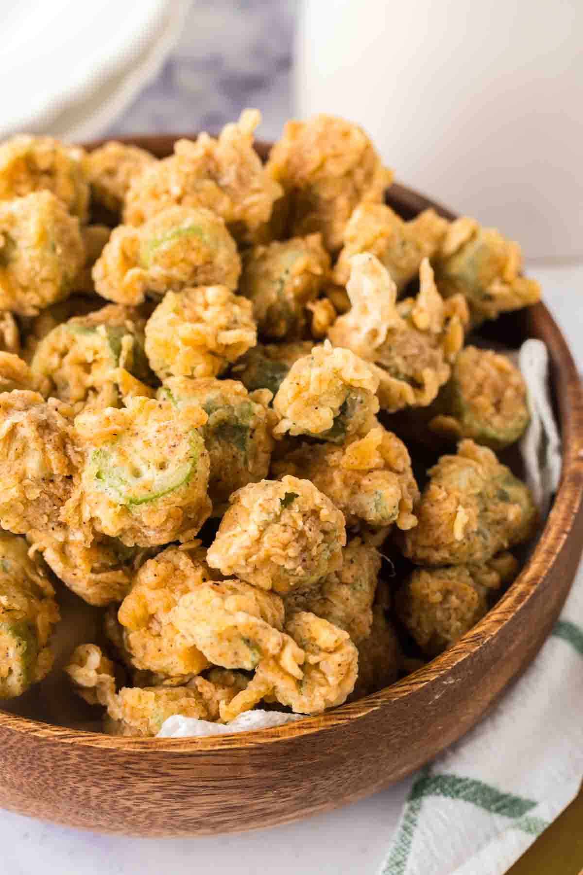 small wooden bowl with bits of fried okra stacked in