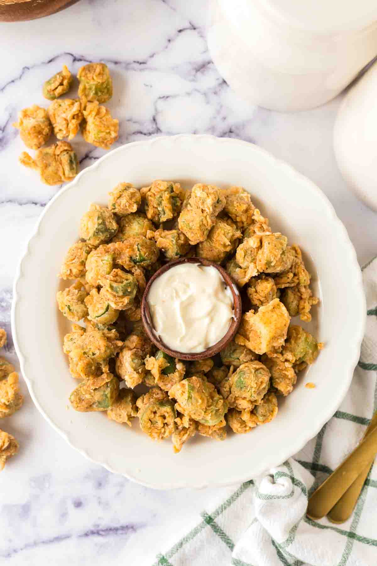 small white plate with a ring of fried okra around a dish of aioli