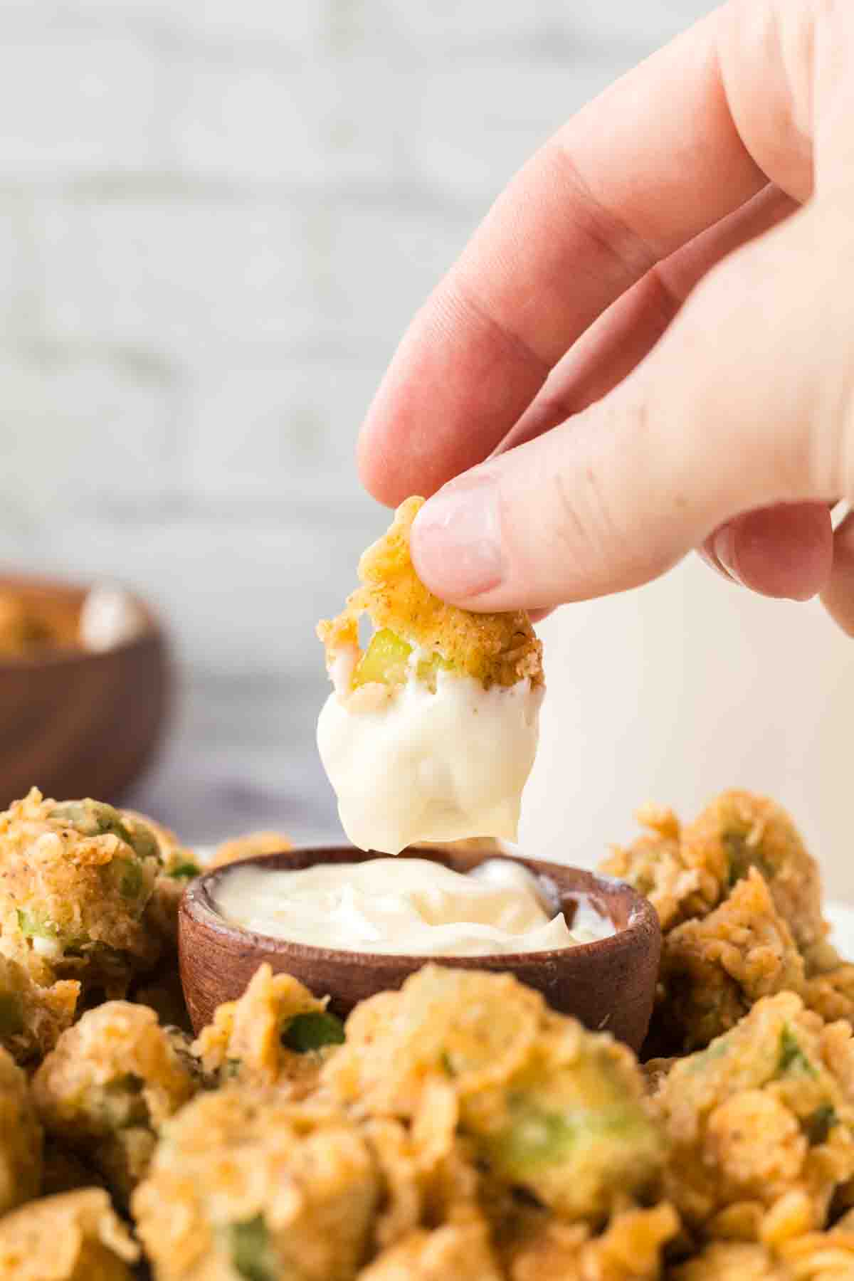 POV hand dipping a fried okra bite into aioli