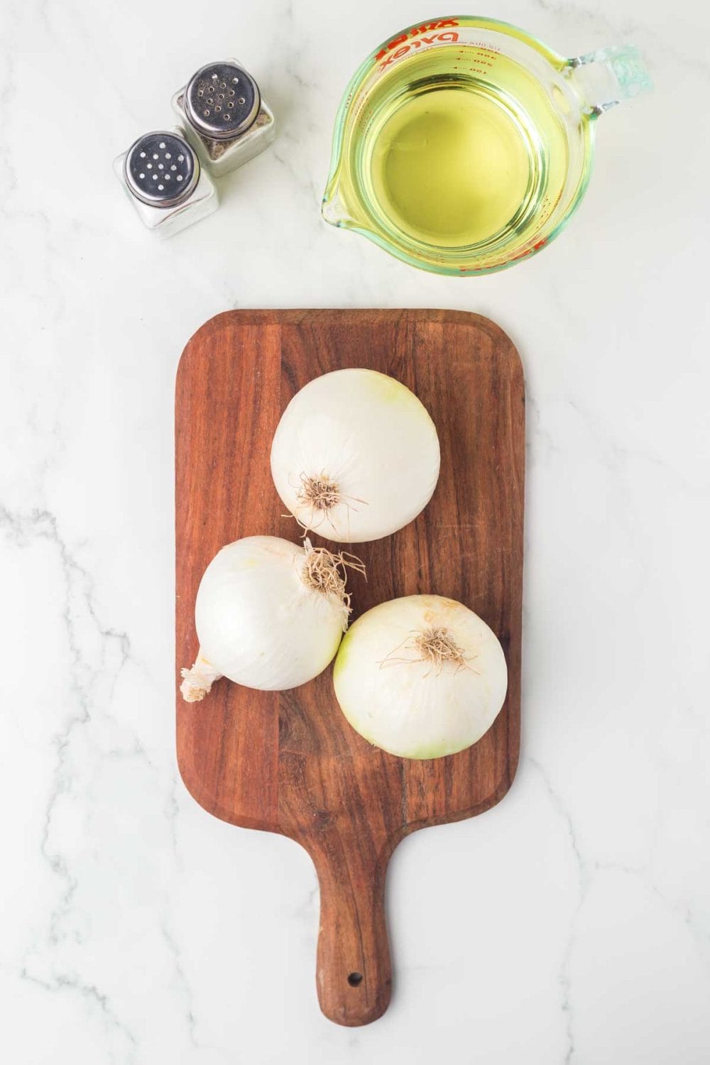 whole white onions over a wooden board for fried onions recipe