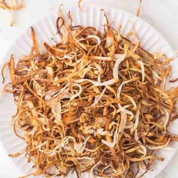 white plate with a nest of thinly sliced fried onions