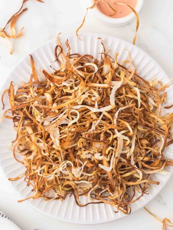 white plate with a nest of thinly sliced fried onions