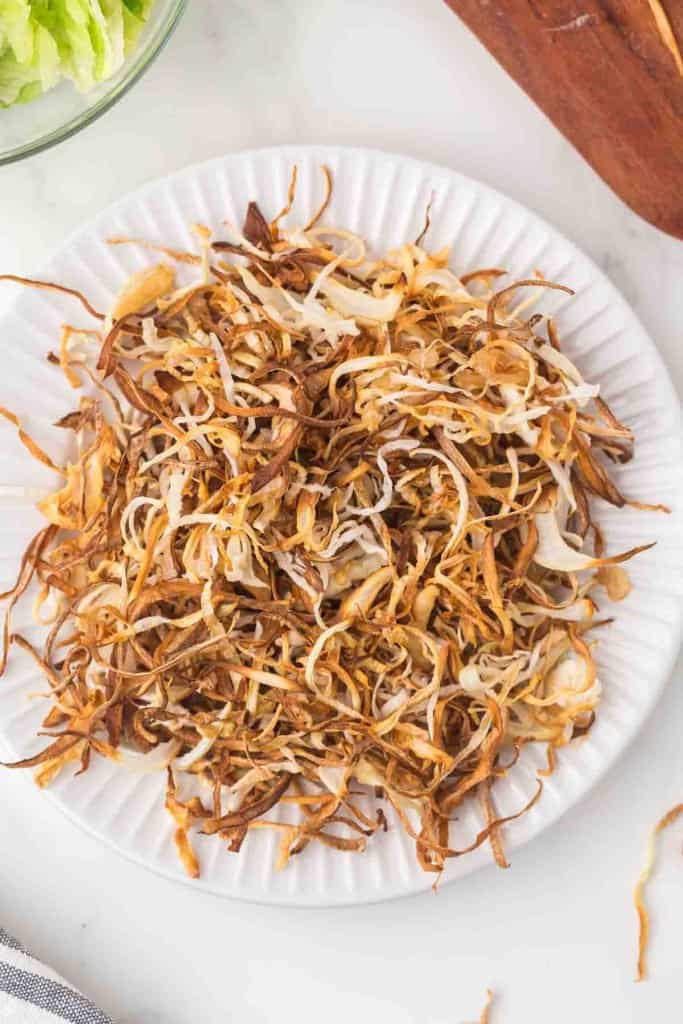 white plate with shreds of fried onions
