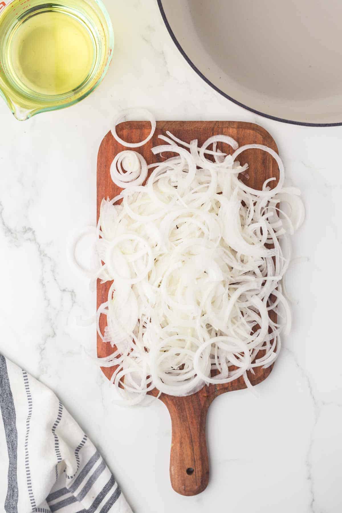 a pile of sliced white onions over a wooden board for fried onions recipe