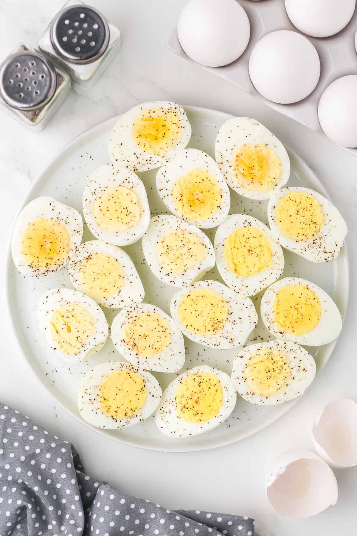 a plate of halved hard boiled eggs with seasoning on top