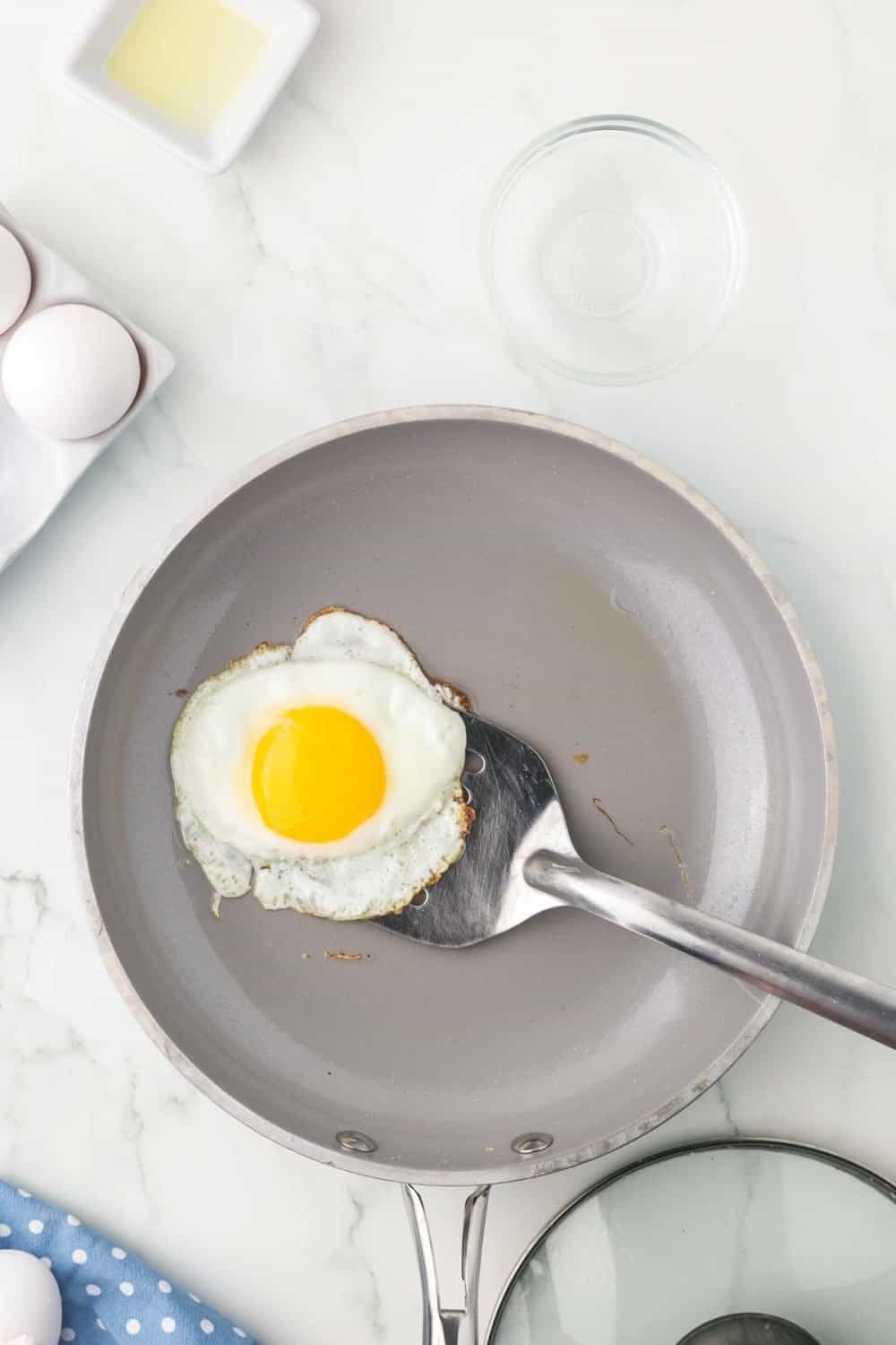 sautéed pan with an egg cooking with a spatula