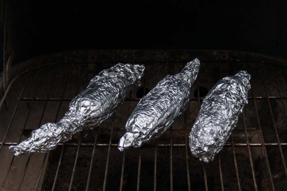 corn on the cob over the grill in tin foil