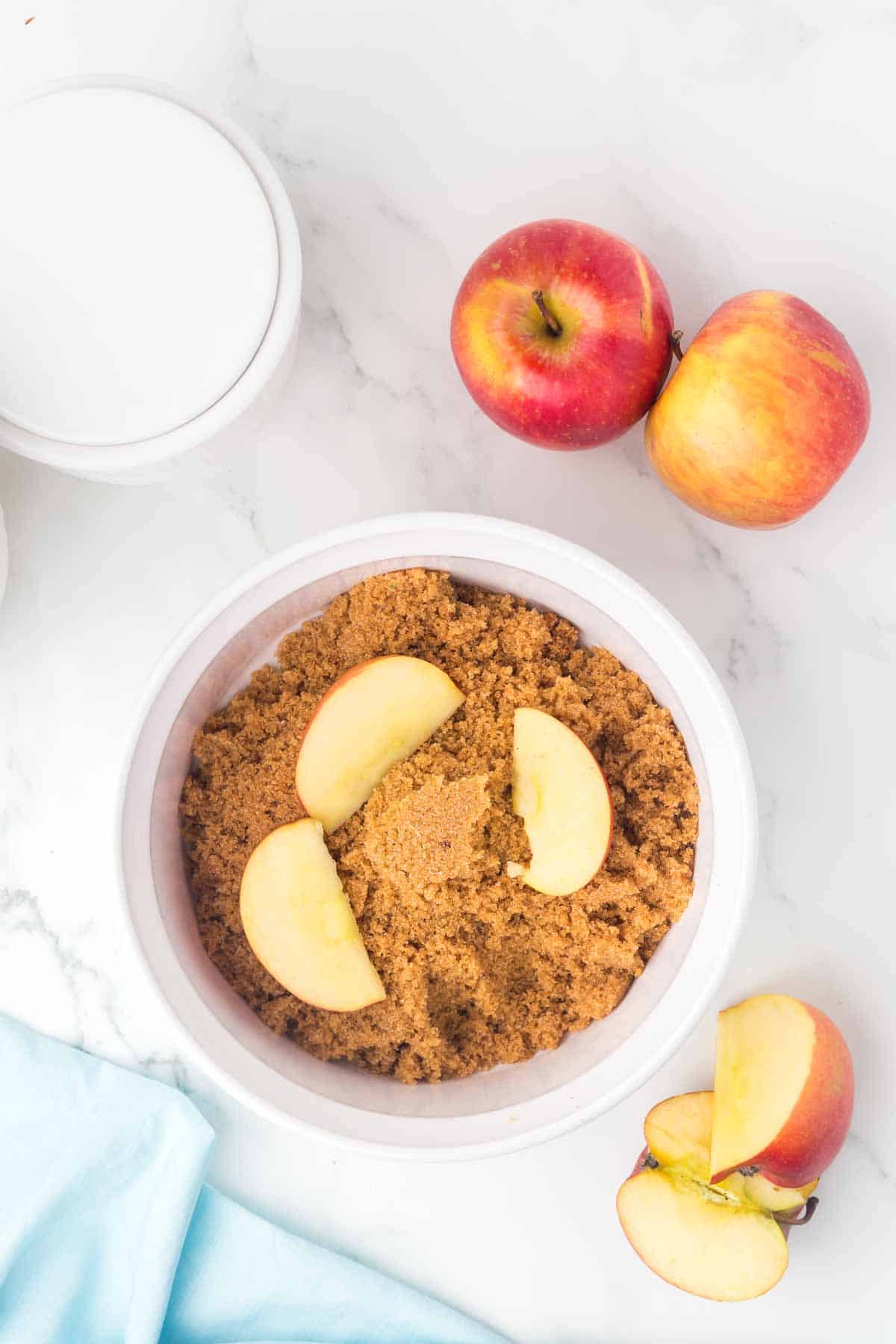 top view of softened brown sugar in a dish with sliced apples in it