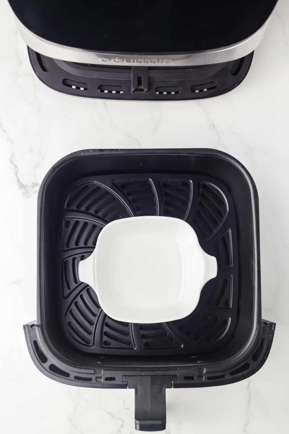 top view of an air fryer basket with a white dish in the middle