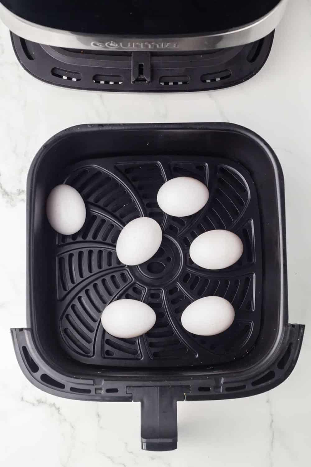 top view of an air fryer basket with whole eggs inside