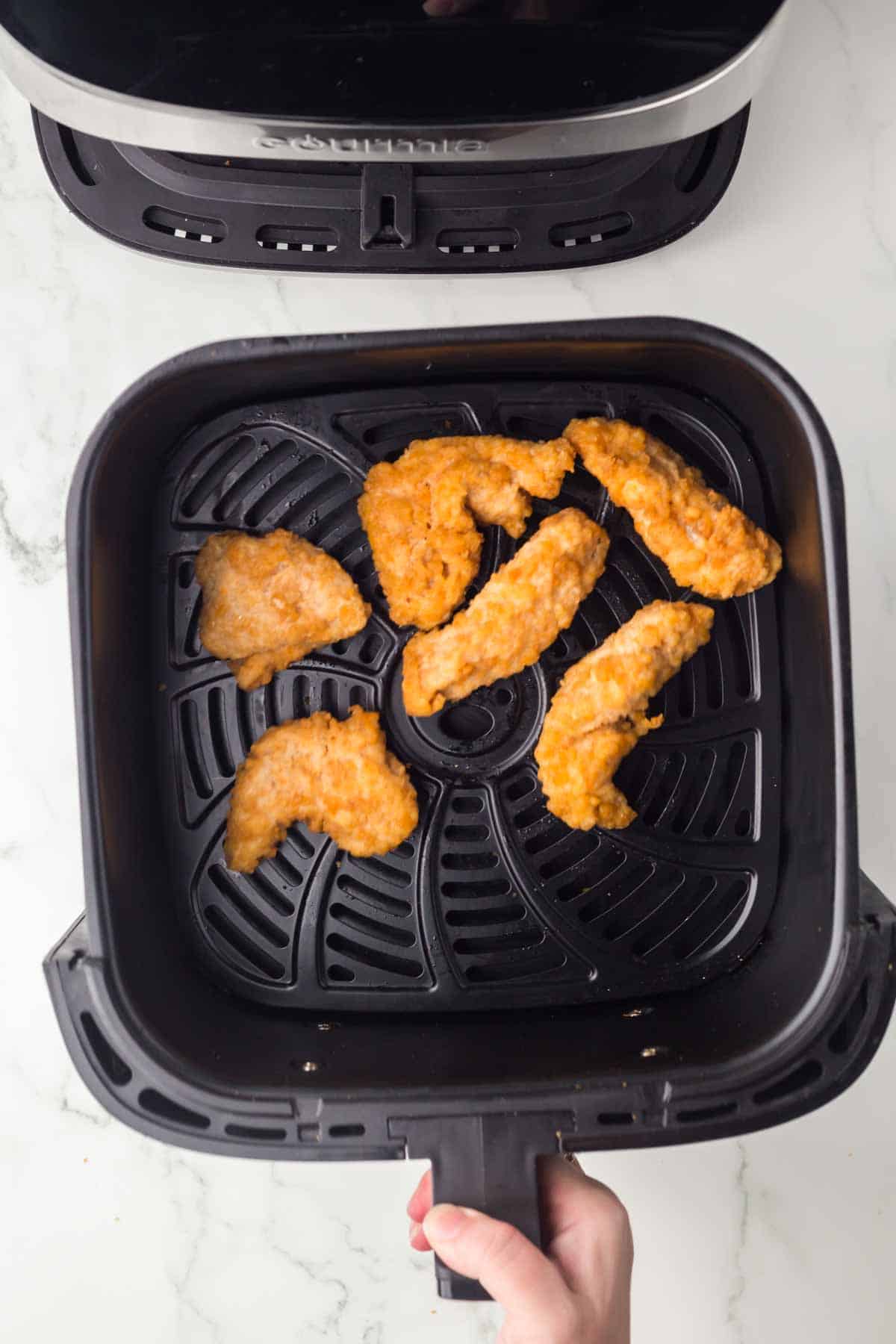 top view of an air fryer basket with with cooked chicken inside