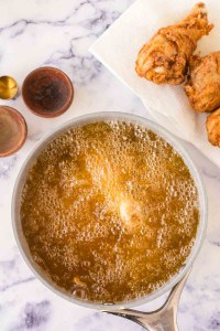 oil bubbling with chicken being friend in a sauce pan.