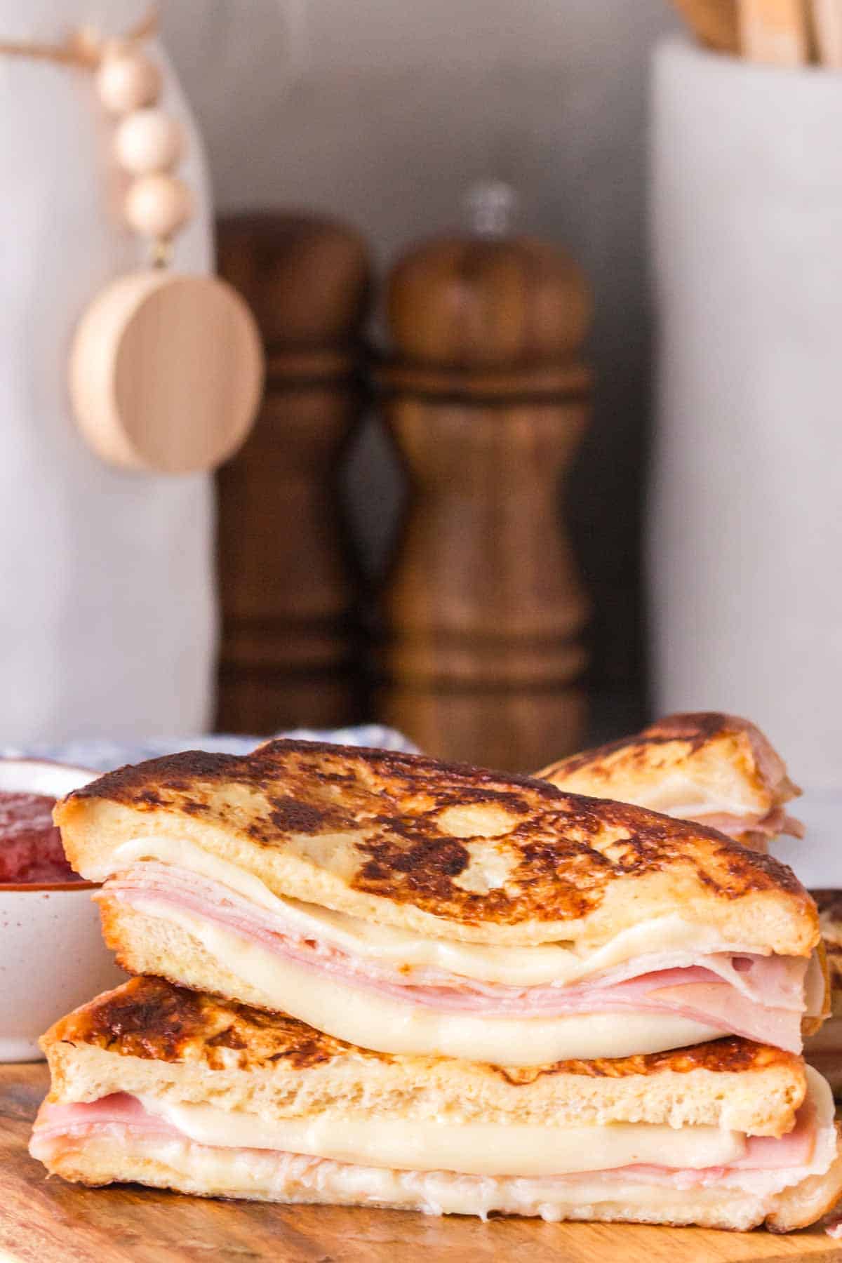 side view sliced in half of a grilled monte cristo sandwich dipped in eggs and grilled then displayed on a wood block