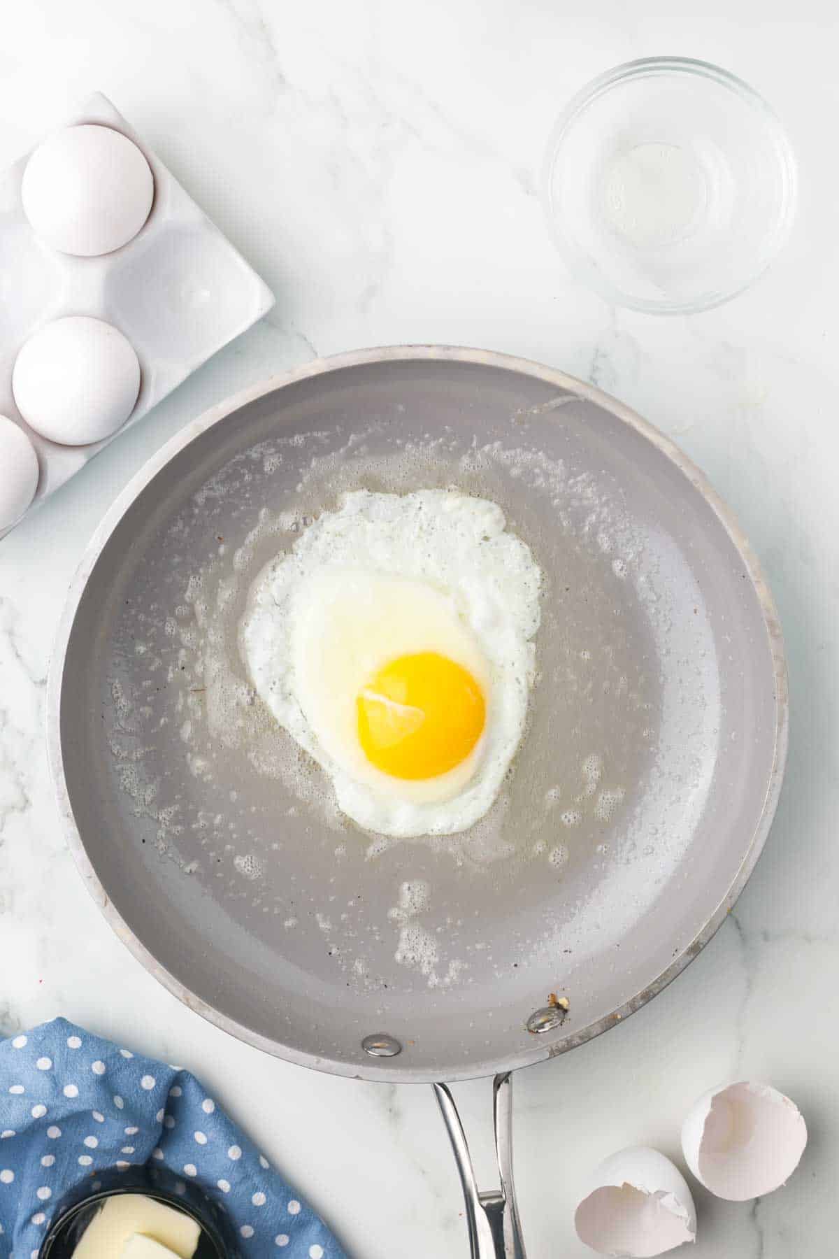 sautéed pan with an over easy egg cooking in it