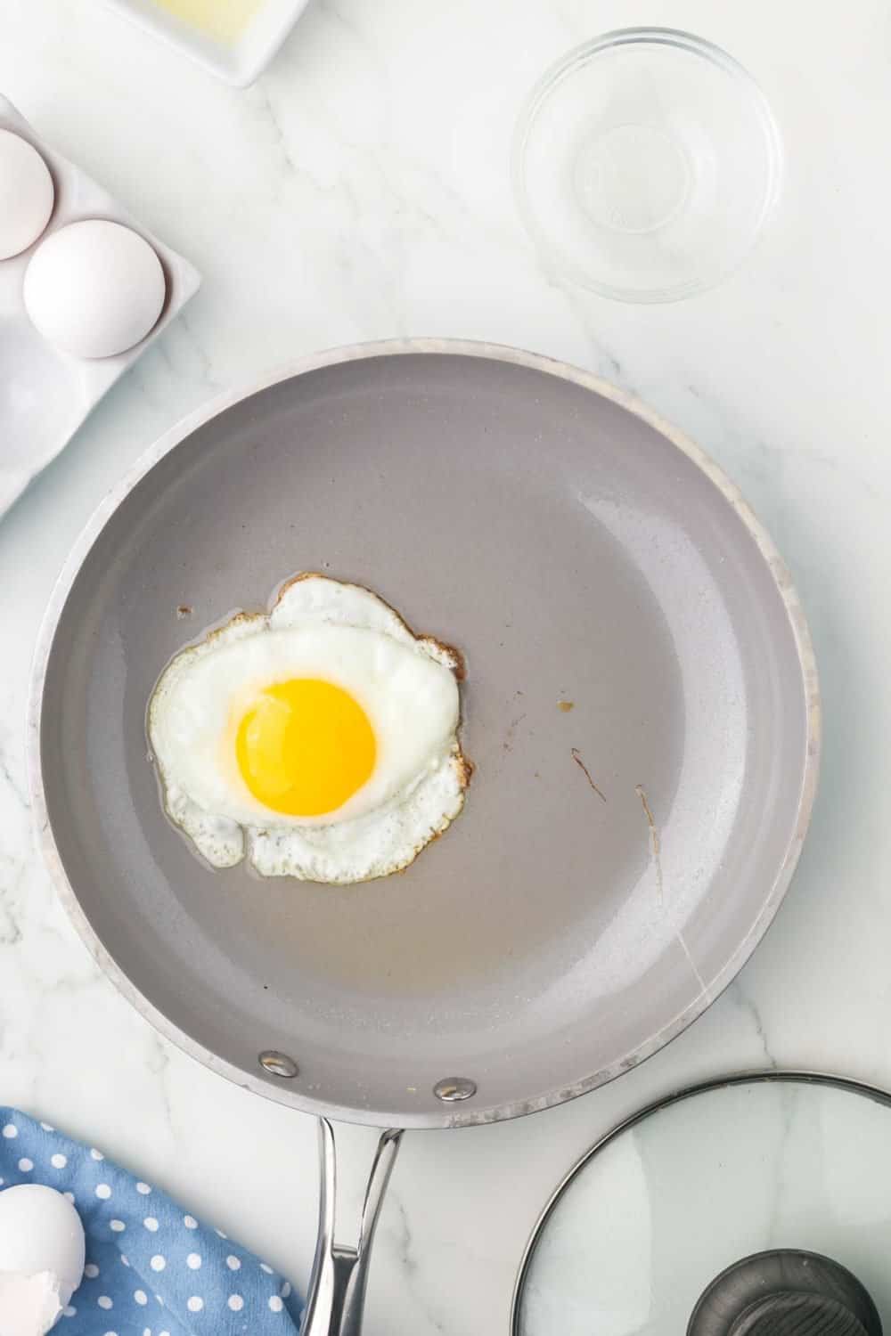 sautéed pan with an over easy egg cooking in it