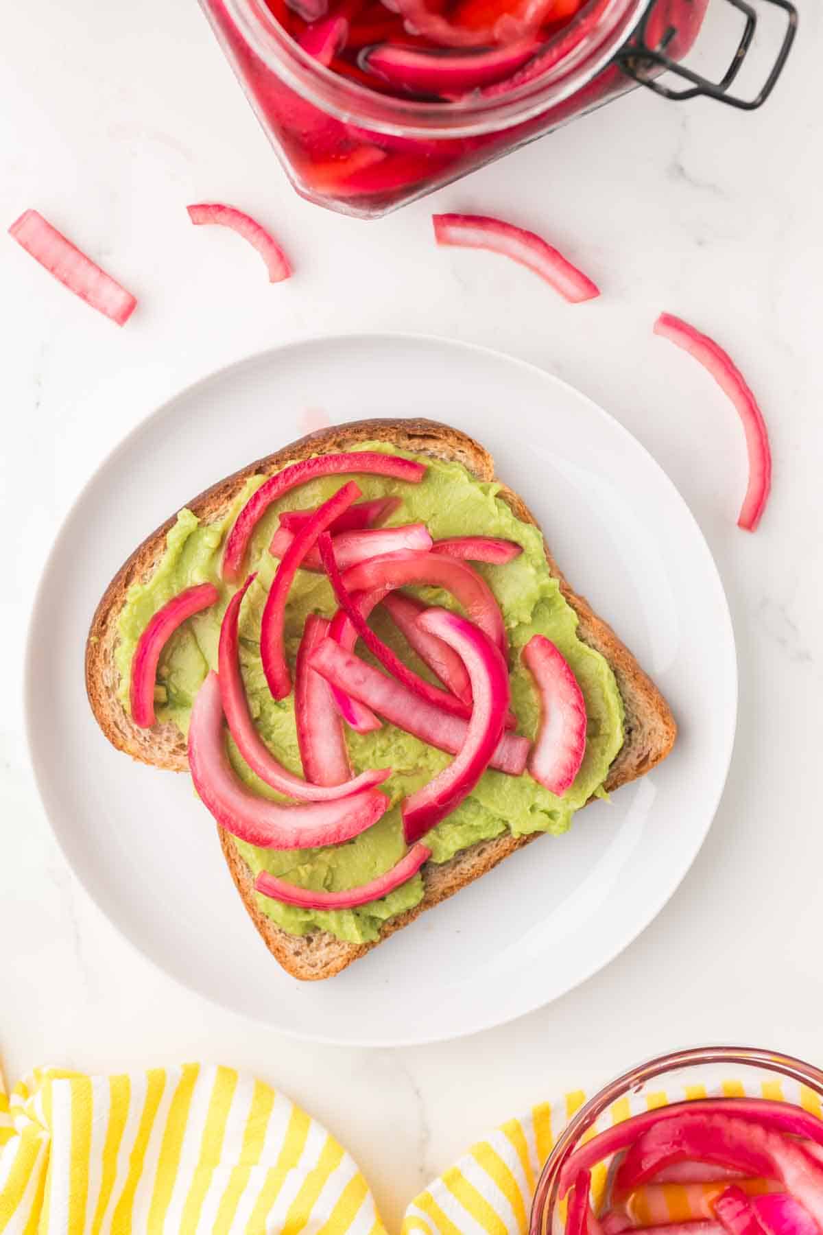 pickled red onions on top of a slice of wheat avocado toast