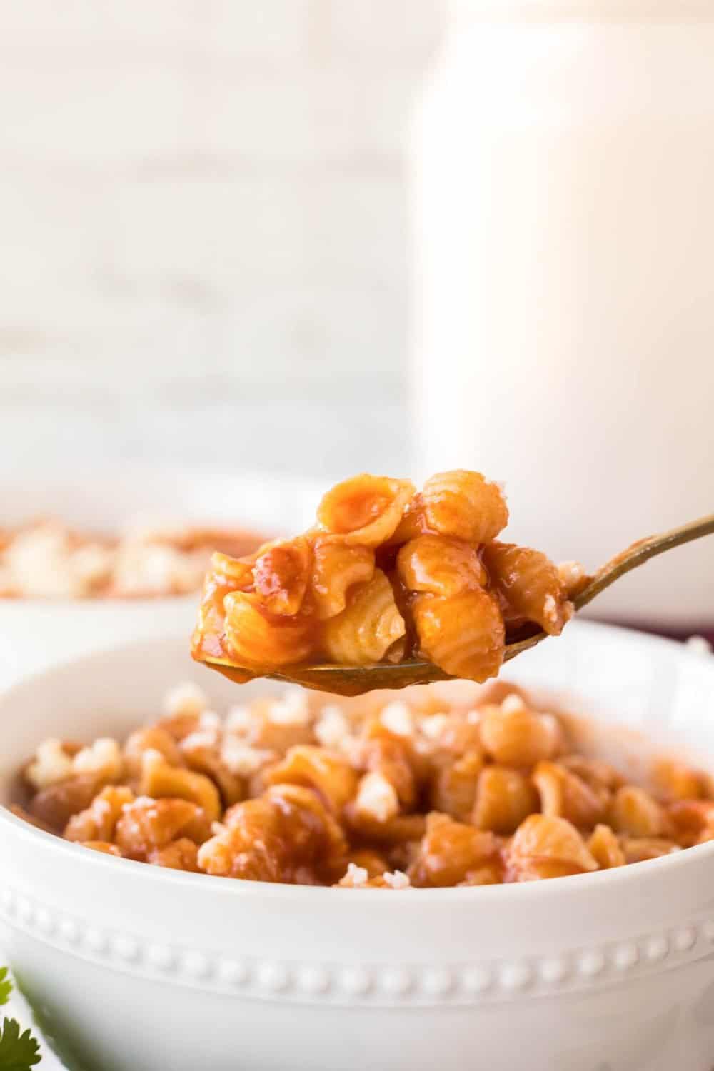 POV spoonful of sopitas being scooped out of a white bowl