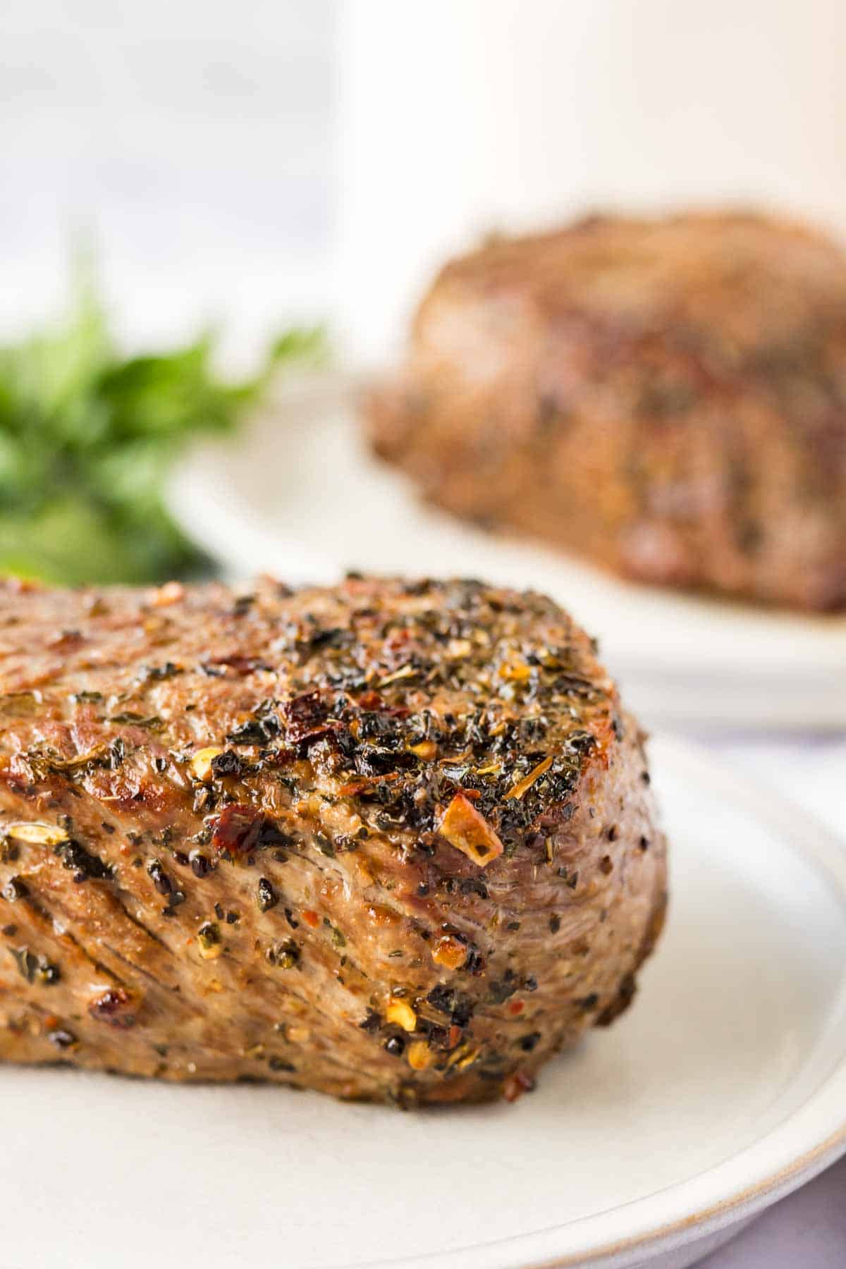 side view of marinated cooked steak on a white plate