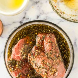 steak inside a clear mixing bowl with the marinade