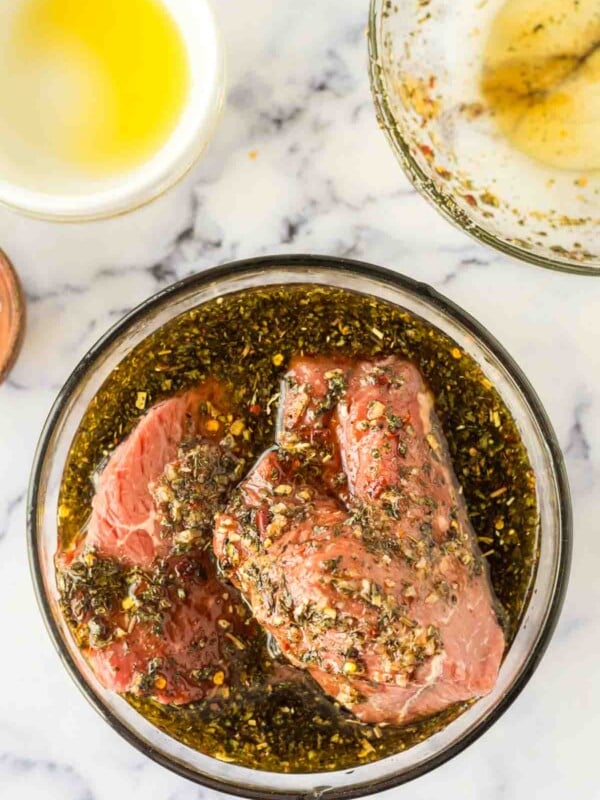 steak inside a clear mixing bowl with the marinade