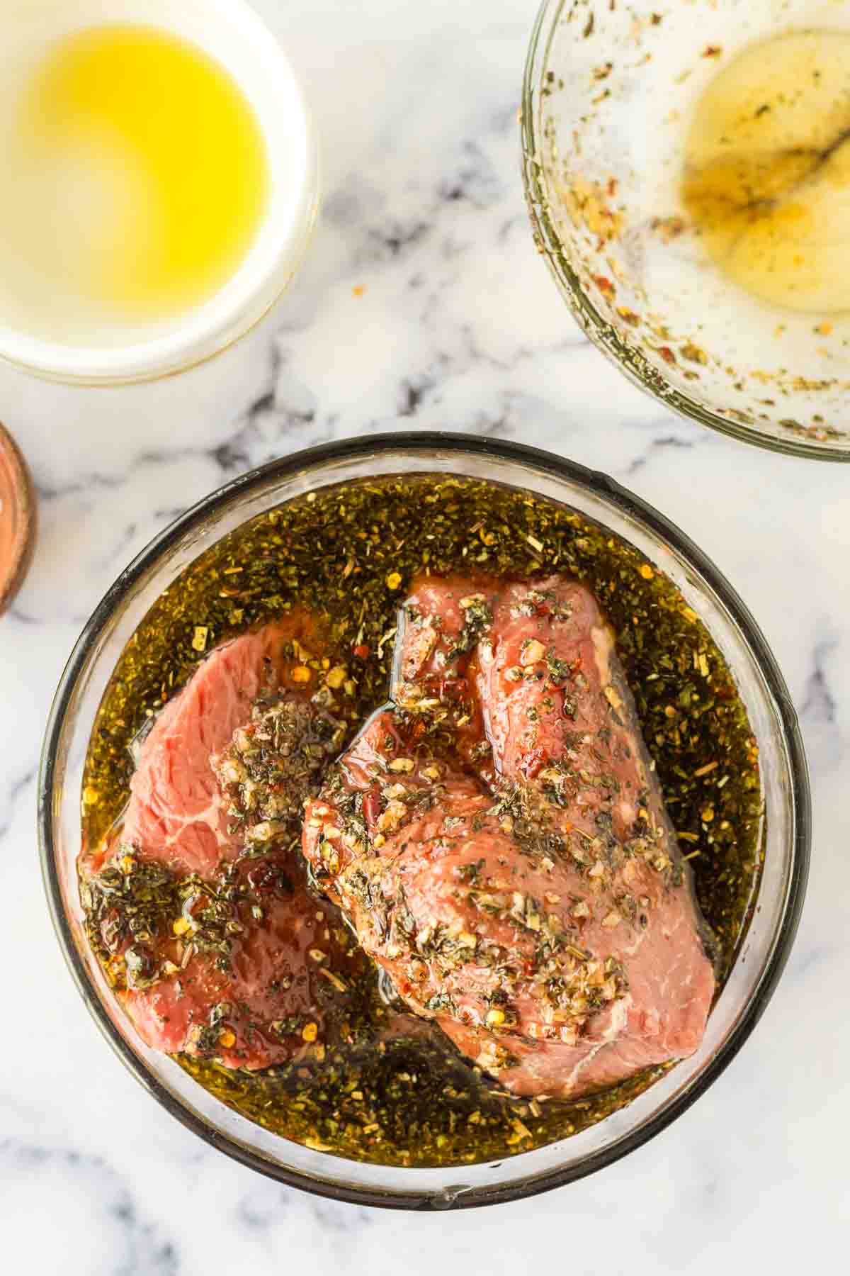 steak inside a clear mixing bowl with the marinade