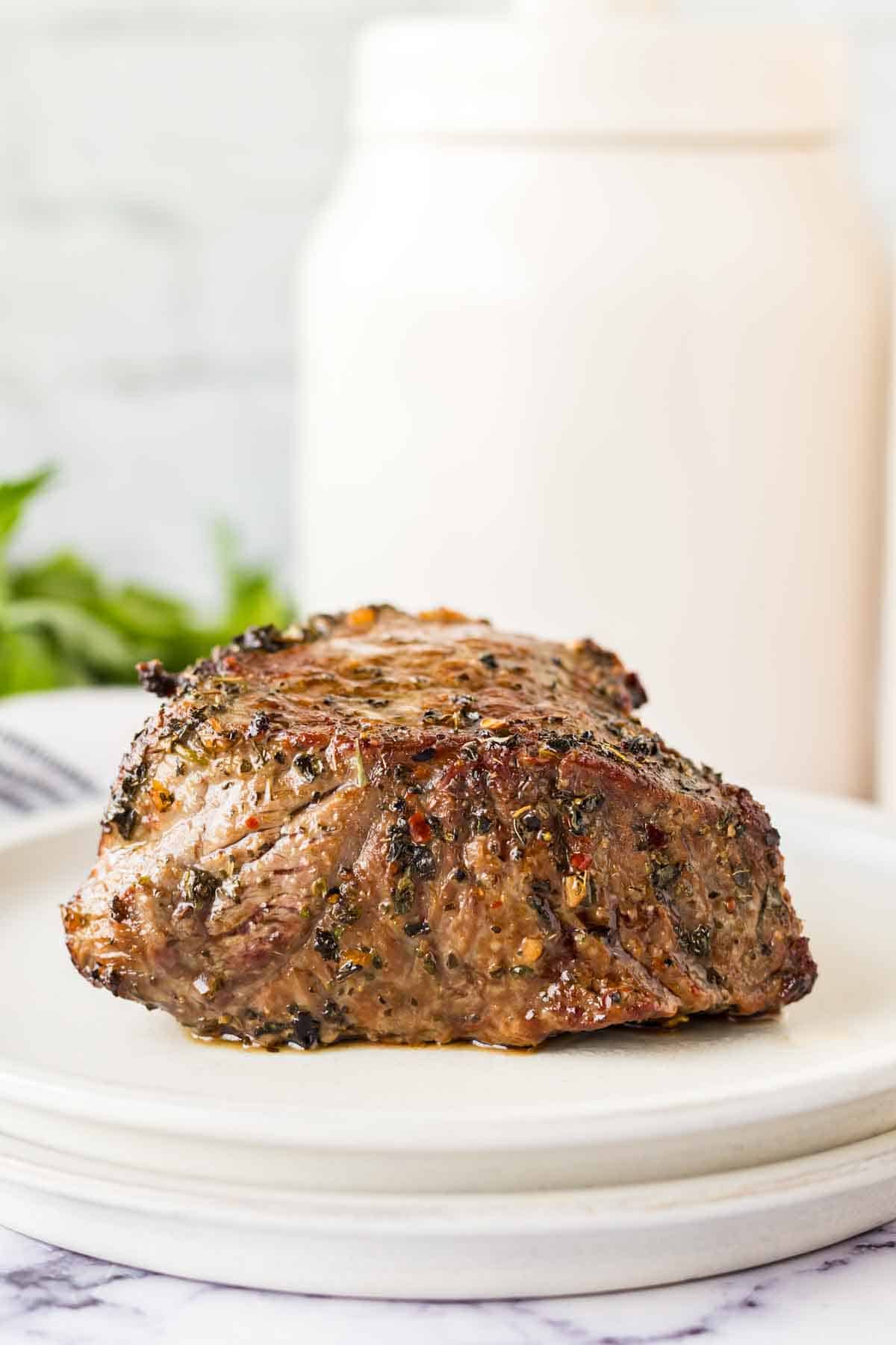 side view of a white plate with a marinated steak