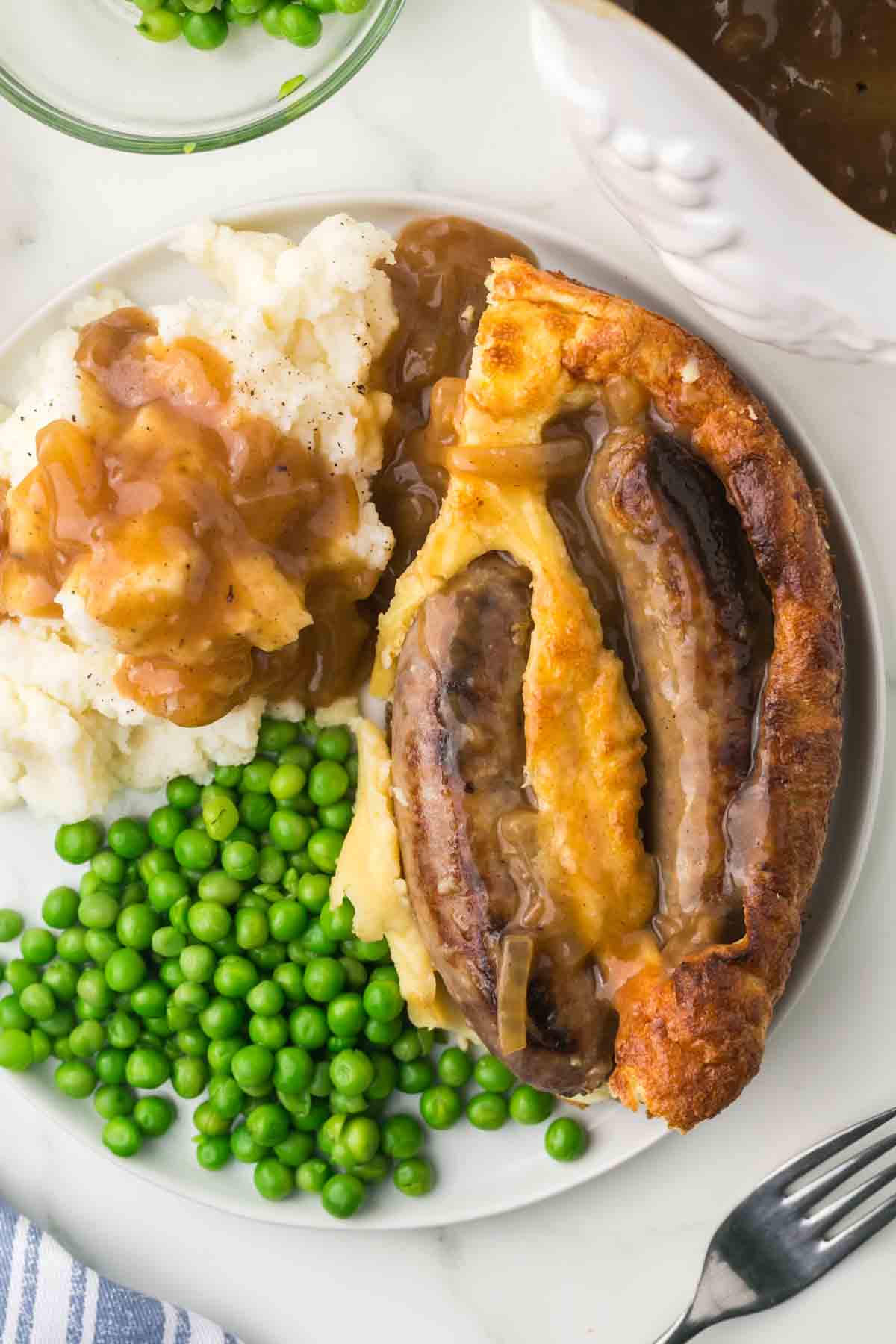 top view of plated serving of toad in a hole recipe with mash potato and peas