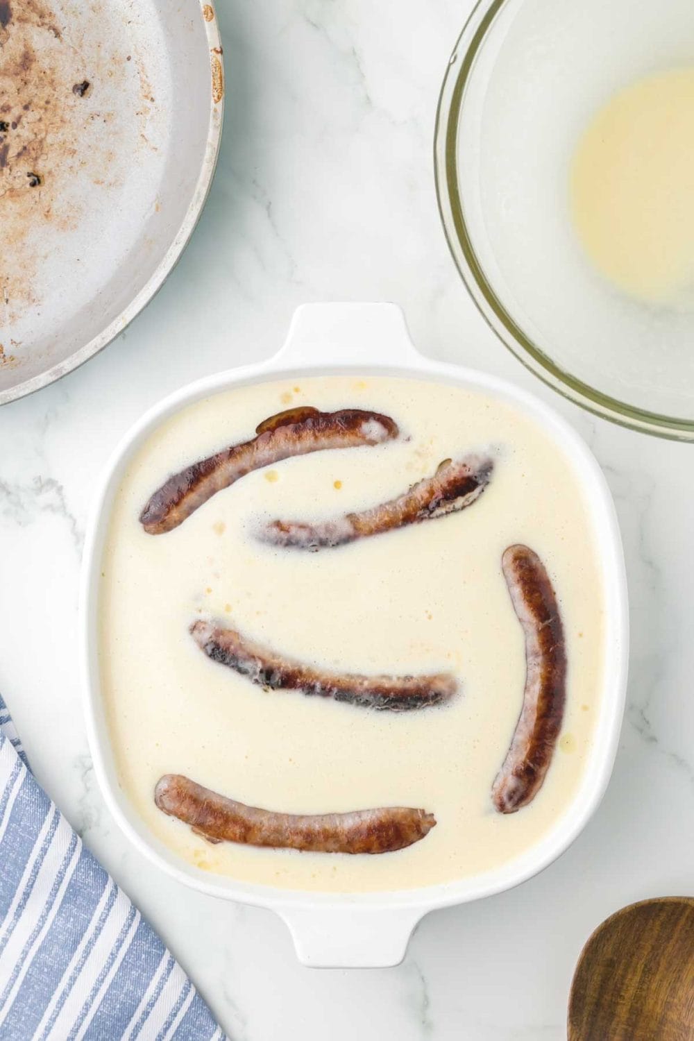 cooked sausage whole inside the wet dough for toad in a hole recipe