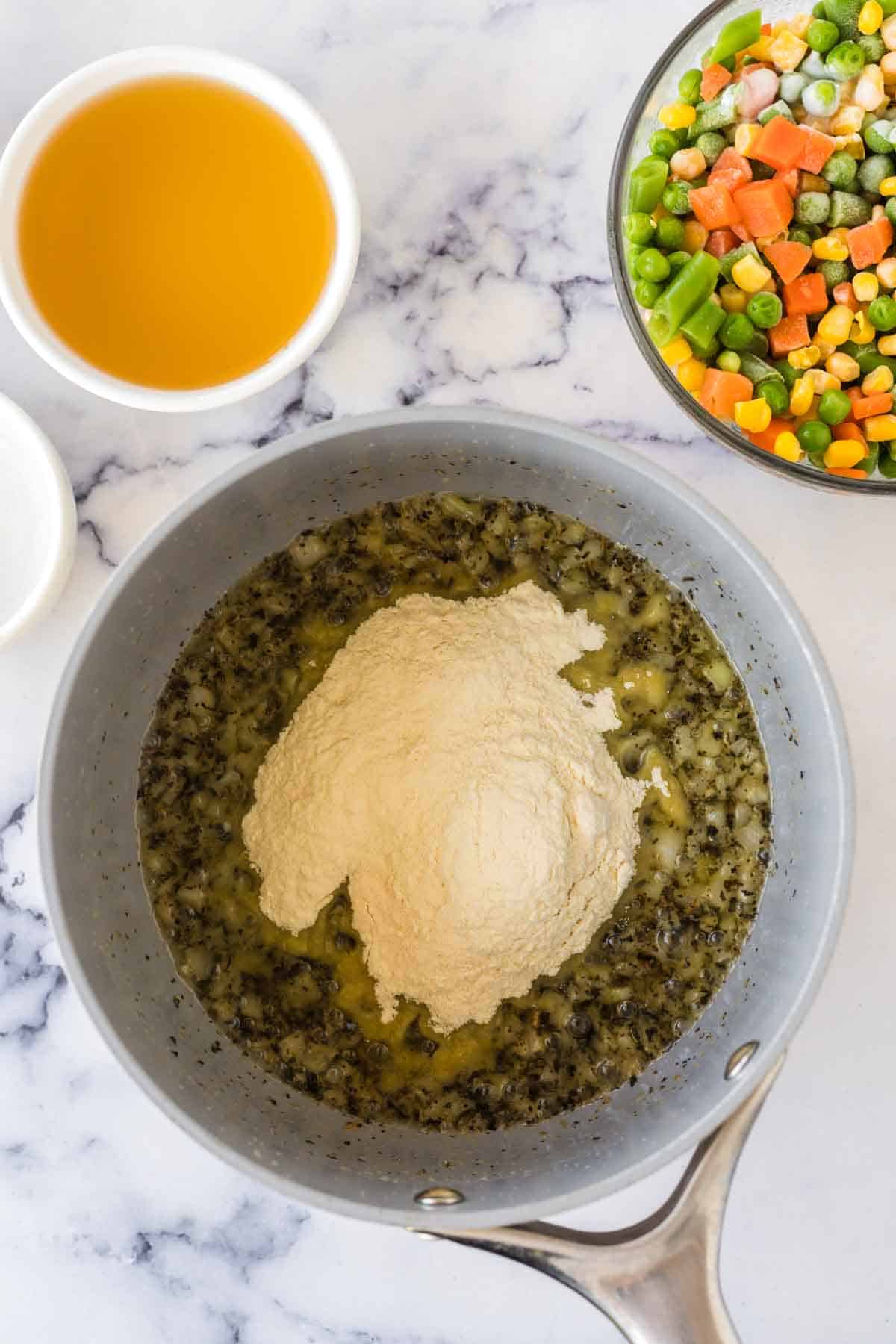 Adding flour to the pot of ingredients for turkey pot pie. 