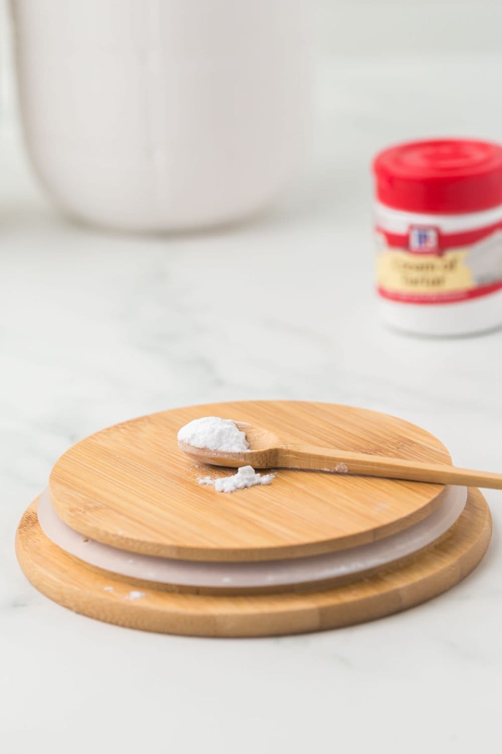 small jar of McCormick cream of tartar with a red lid on a wooden board