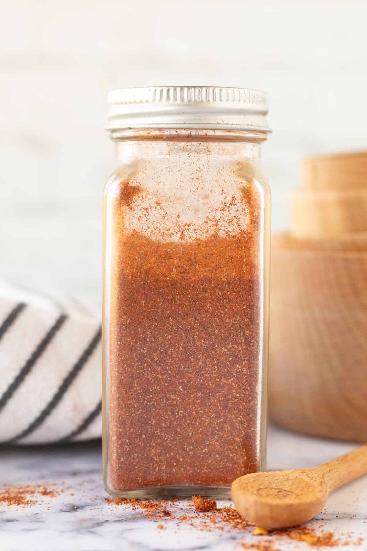 a glass container with a silver lid with homemade adobo seasoning